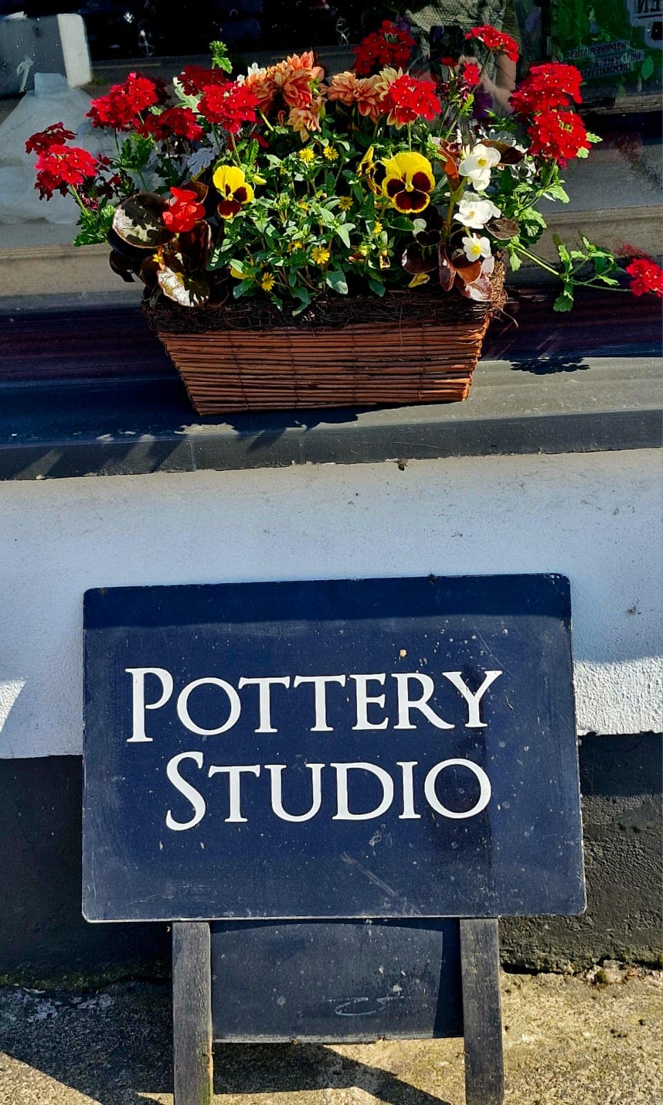 The Pottery Studio sign beneath a window box of summer flowers